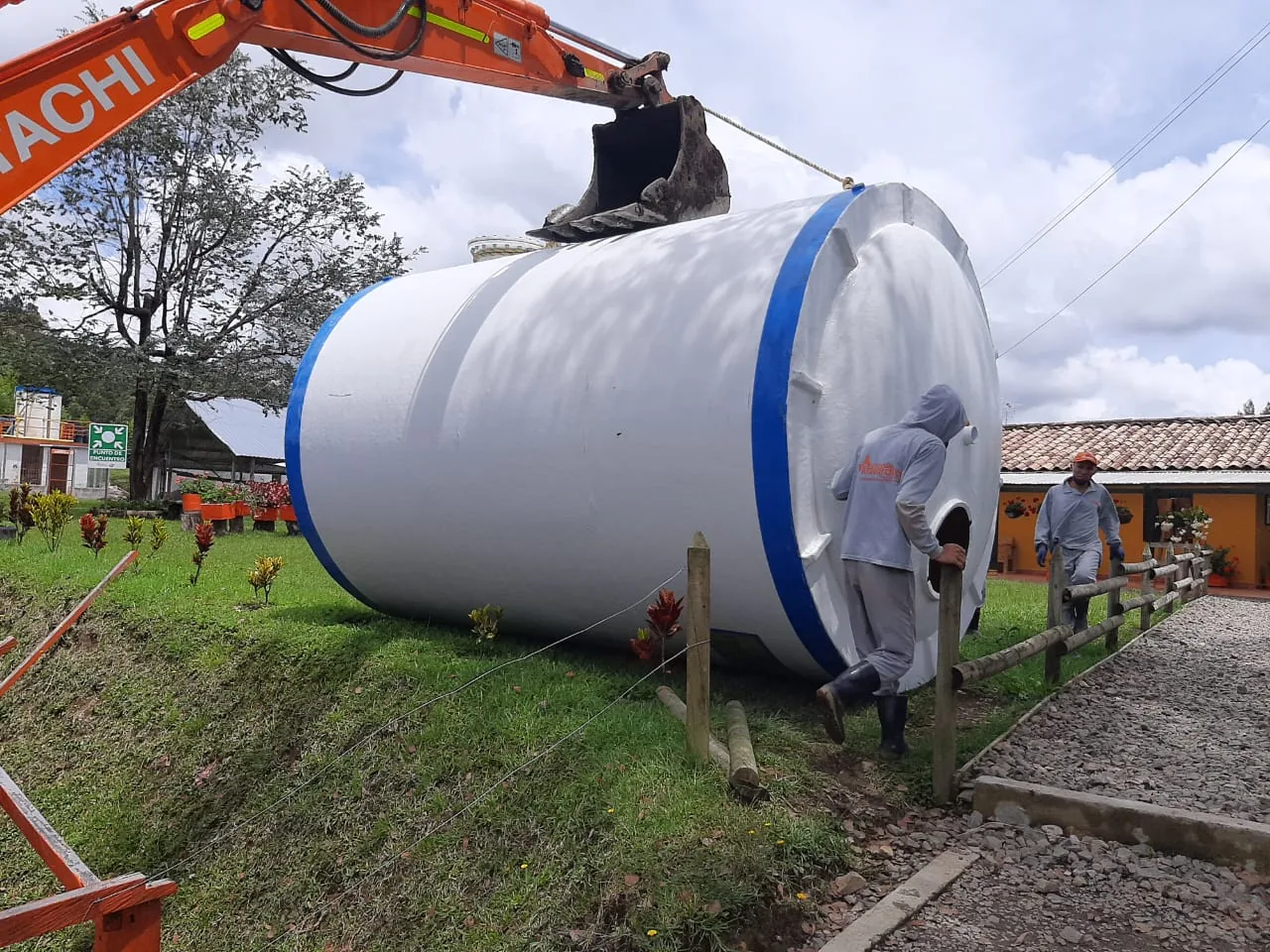 Maniobra de un tanque en fibra de vidrio con retroexcavadora en una finca.