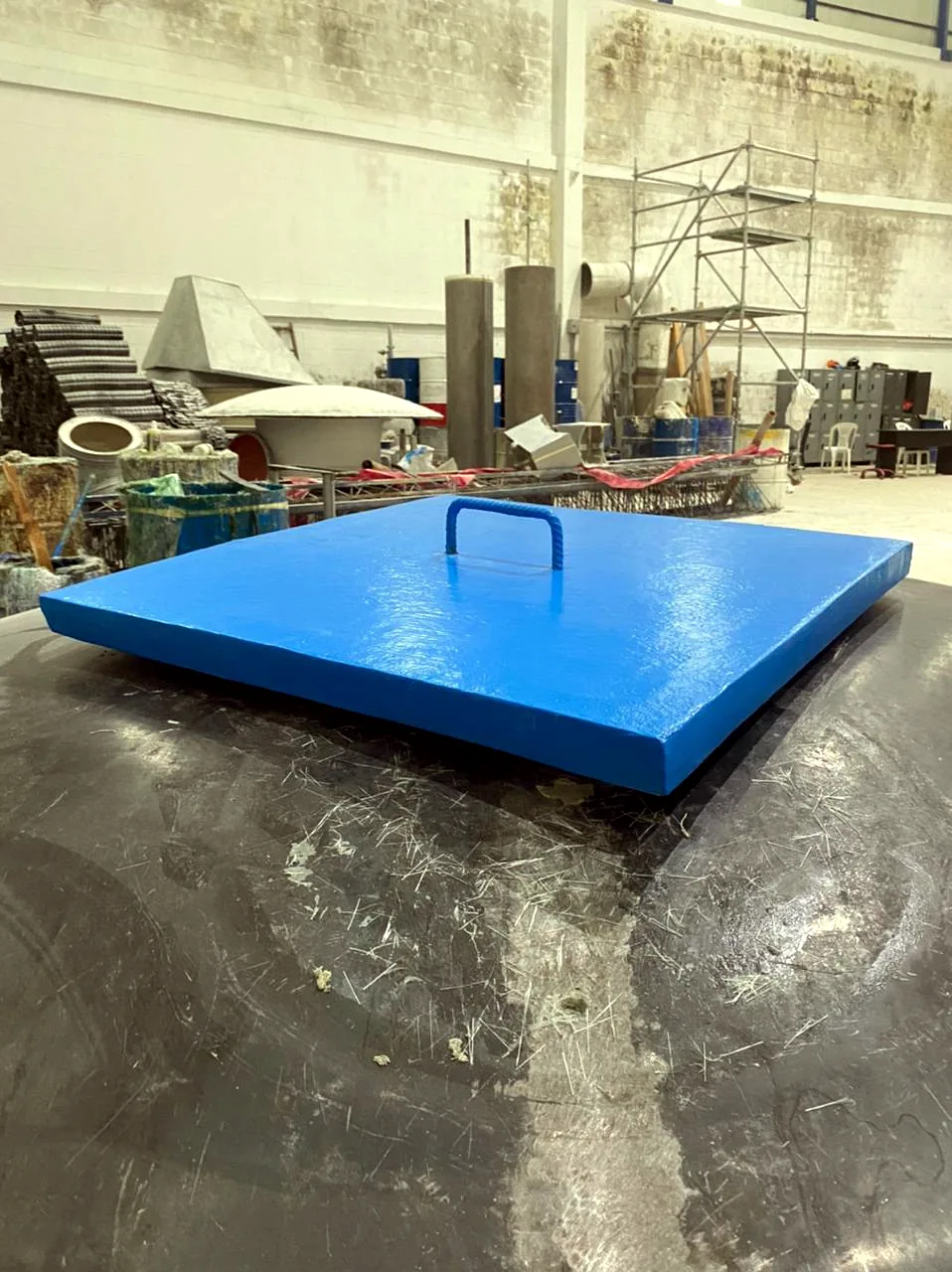 Tapa en PRFV vista de perfil sobre la mesa del taller: se le alcanza a ver el espesor del laminado.